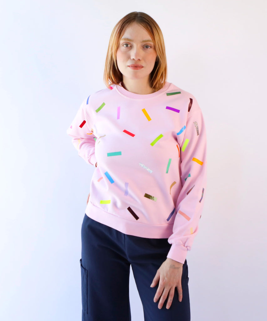 woman wearing a pink cotton sweatshirt with colorful sprinkles confetti pattern