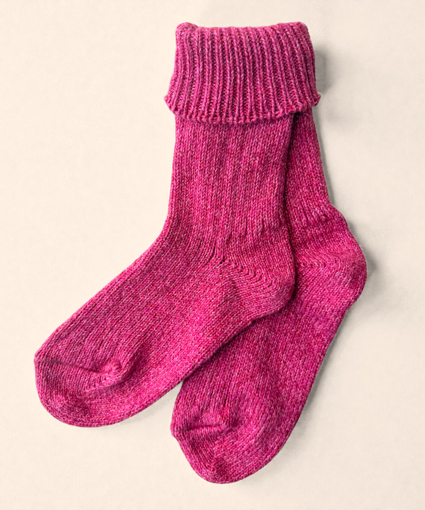 A pair of bright pink glittery knitted cotton socks on a beige background. 
