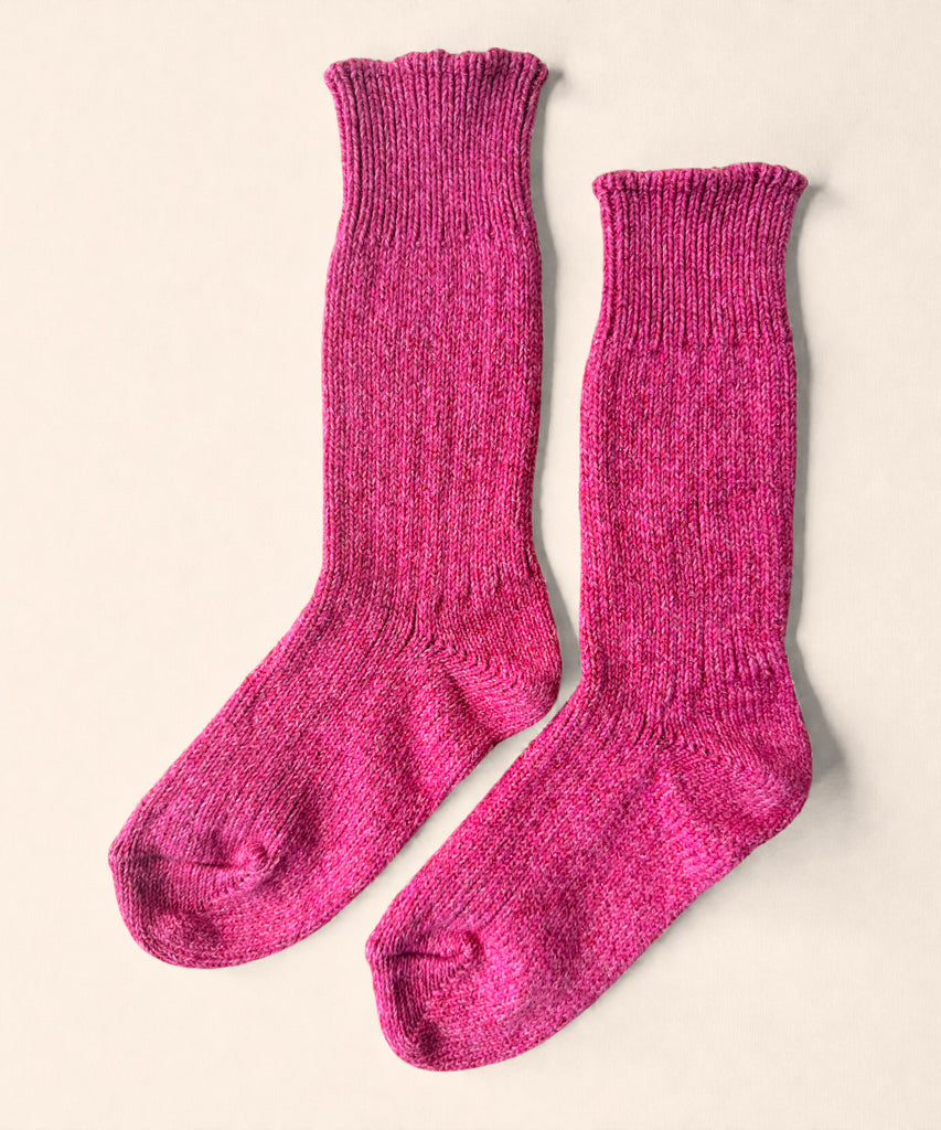 A pair of bright pink glittery knitted cotton socks on a beige background. 