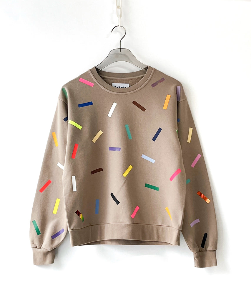 Beige cotton sweatshirt with colorful sprinkles pattern on a hanger