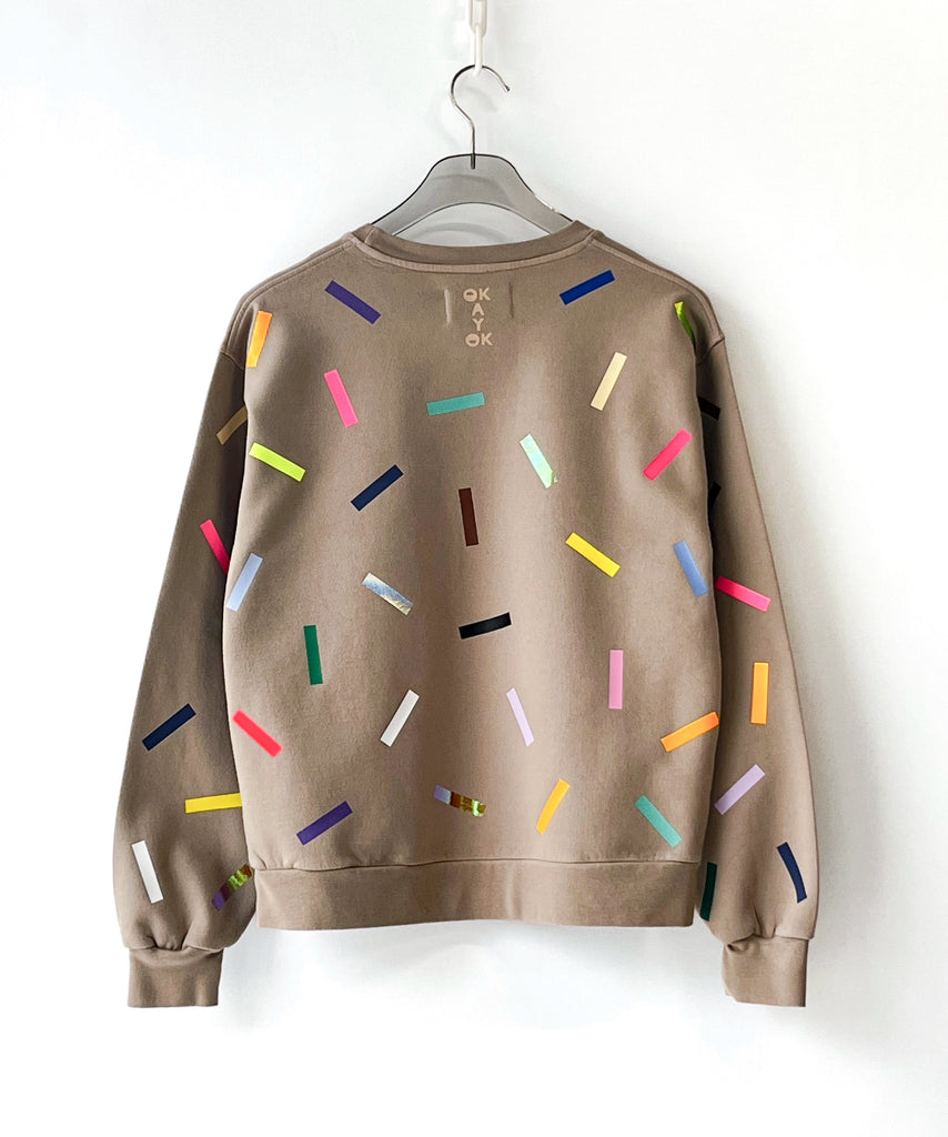 Beige cotton sweatshirt with colorful sprinkles pattern on a hanger