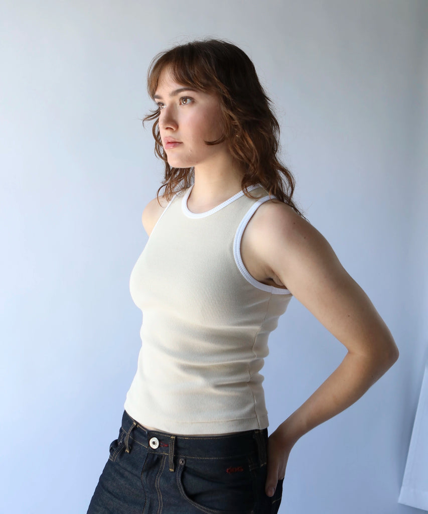 woman wearing a beige cotton ribbed tank top with white trim 