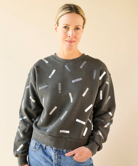 a woman wears a grey sweatshirt with silver and pewter confetti sprinkle print design