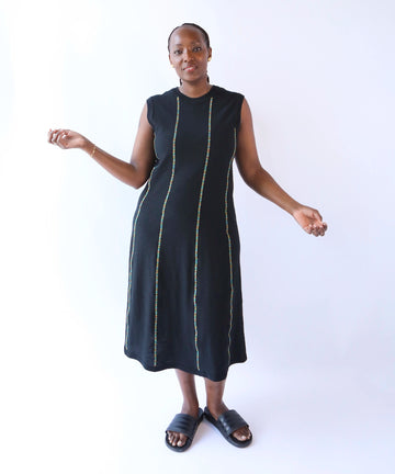 Woman wearing a black sleeveless cotton dress with multicolor trim