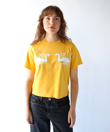woman wearing a cotton tshirt in mustard yellow with two white swans graphic